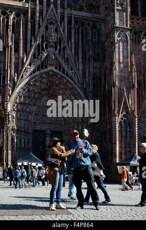 Tourist with camera on selfie stick in front of Cathedral of Our Lady of Strasbourg, Alsace, France Stock Photo