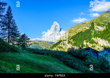 Matterhorn peak with cabin and pines on an early morning in the summer. July, 2105. Matterhorn, Switzerland. Stock Photo
