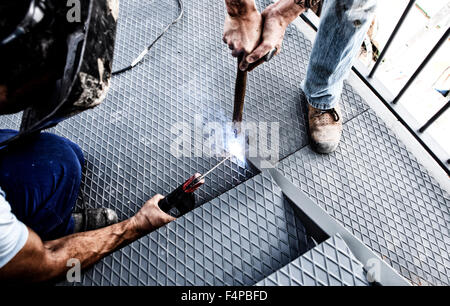 Two men working over iron platform with arc welding Stock Photo