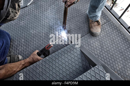 Two men working over iron platform with arc welding Stock Photo