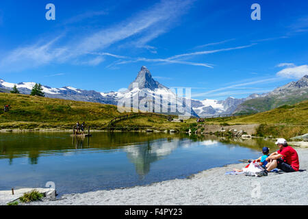 People relaxing by the lake under Matterhorn peak in summer. July, 2015. Matterhorn, Switzerland. Stock Photo