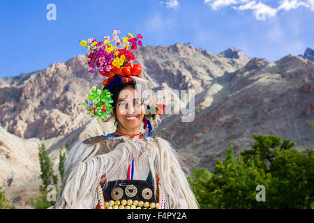 A woman of the Brokpa tribe, an arien race, in her traditional dress with a flower arrangement carried on the head Stock Photo