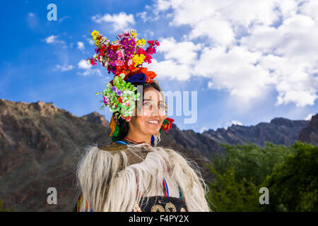 A woman of the Brokpa tribe, an arien race, in her traditional dress with a flower arrangement carried on the head Stock Photo