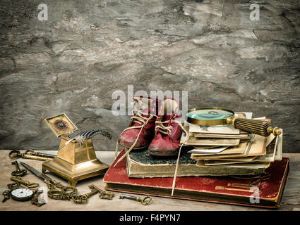 Antique books and photos, writing accessories and old baby shoes. Vintage style toned picture Stock Photo