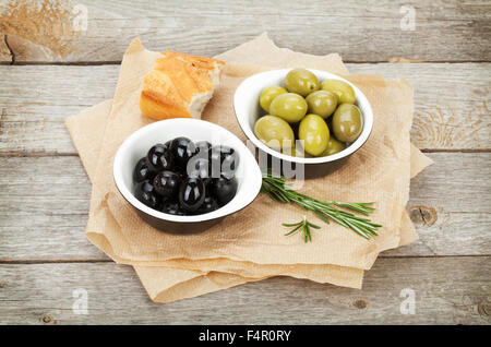 Italian food appetizer of olives, bread and herbs on wooden table background Stock Photo