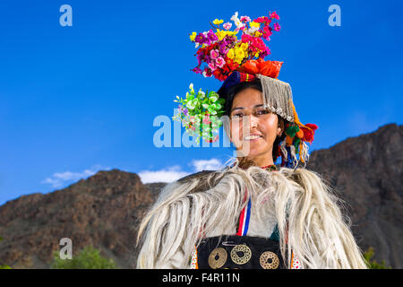 A woman of the Brokpa tribe, an arien race, in her traditional dress with a flower arrangement carried on the head Stock Photo