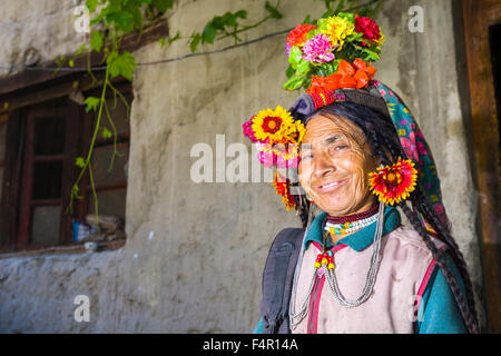 A woman of the Brokpa tribe, an arien race, in her traditional dress with a flower arrangement carried on the head Stock Photo