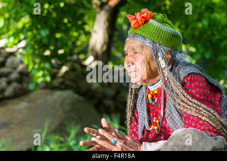 A woman of the Brokpa tribe, an arien race, in her traditional dress with a flower arrangement carried on the head Stock Photo