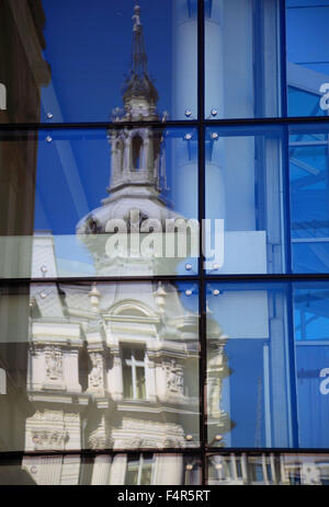 historic townhouse is reflected in glass facade of a modern office building in Bucharest, Romania Stock Photo