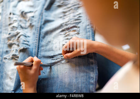 young girl is cutting her jeans (MR) Stock Photo