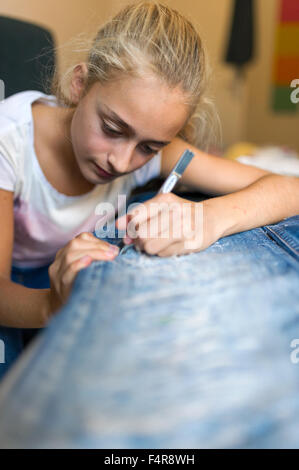 young girl is cutting her jeans (MR) Stock Photo