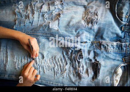 young girl is cutting her jeans (MR) Stock Photo