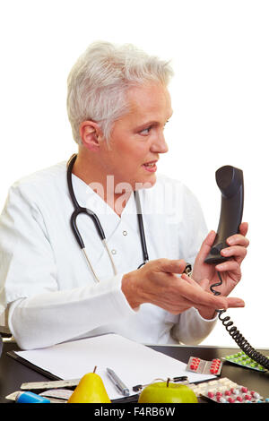 Doctor sitting at his desk and making a phone call Stock Photo