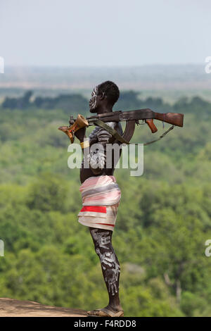 Young male Karo tribe boy with AK-47 rifle . Omo Valley, Ethiopia