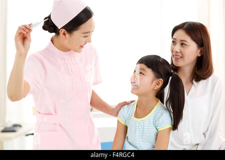 The female nurse is giving the little girl the temperature. Stock Photo