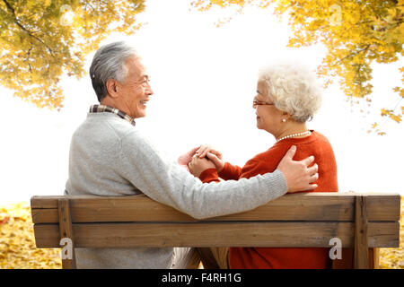 Happy old couple sitting on a bench Stock Photo