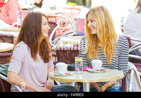 Two girls have a talk in a street cafe Stock Photo