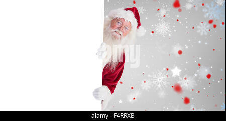 Composite image of santa looks out behind a wall Stock Photo