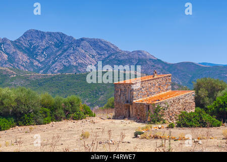 Rural landscape with small abandoned stone house and mountains on the horizon. Piana region, South Corsica, France Stock Photo