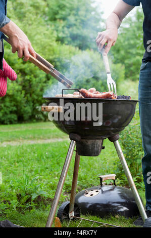 Sweden, Ostergotland, Vikbolandet, Mid-adult men having barbecue in backyard Stock Photo