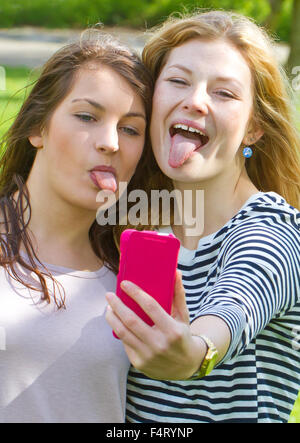 Two teenage girls taking selfie with mobile phone. Stock Photo