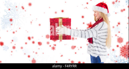 Composite image of festive blonde holding a gift Stock Photo