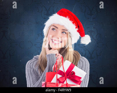 Composite image of festive blonde holding christmas gift and bag Stock Photo