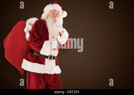 Composite image of santa asking for quiet with bag Stock Photo