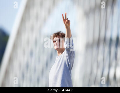 Young Man Standing on the Bridge Making V-sign Stock Photo