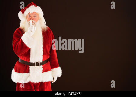 Composite image of santa asking for quiet to camera Stock Photo