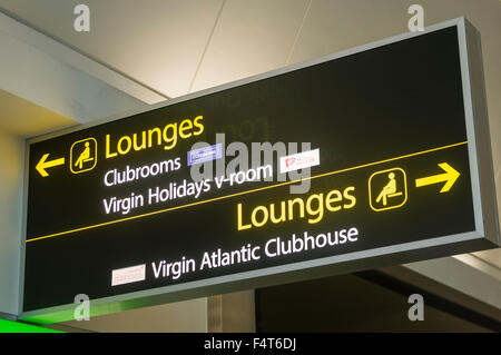 Signs giving the directions to airport lounges, including the Virgin Holidays v-room and Atlantic Clubhouse Stock Photo