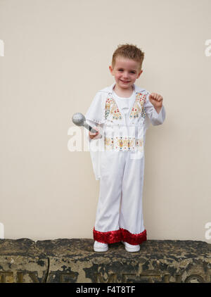 Happy young boy holding microphone and dressed in Elvis Presley suit Stock Photo