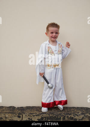 Happy young boy holding microphone and dressed in Elvis Presley suit Stock Photo