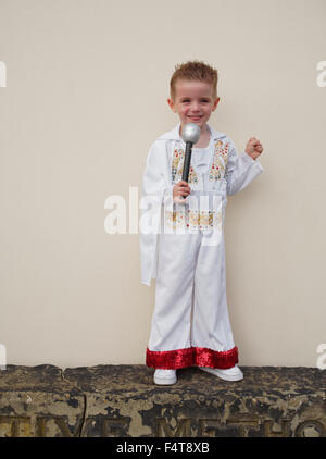 Happy young boy holding microphone and dressed in Elvis Presley suit Stock Photo