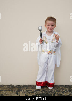 Happy young boy holding microphone and dressed in Elvis Presley suit Stock Photo