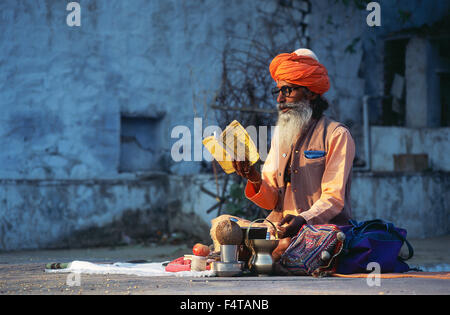 Hindu ascetic ('sadhu') reading a hindu holy book on the ghats at Pushkar Stock Photo
