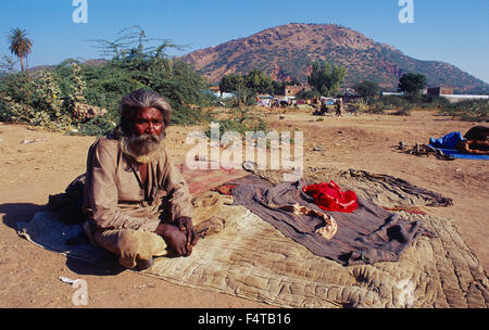 Man belonging to a nomadic group. He is sitting in front of his bed ( Rajasthan, India) Stock Photo