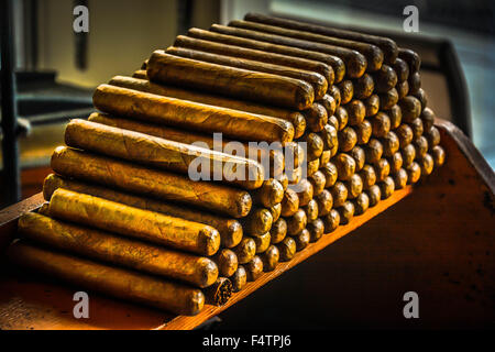 Hand rolled Cuban cigars stacked in cigar factory work bench area Stock Photo