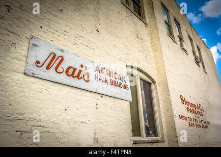 A retro and cool old Historic rustic brick building with parking lot sign advertising African hair braiding and Shrimp & Co Stock Photo