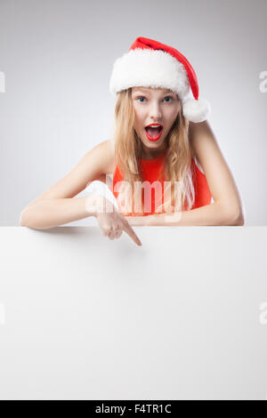 Christmas woman in santa hat pointing empty board Stock Photo