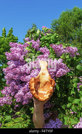 Carved handmade decorative wood spoon near lilac tree. Stock Photo