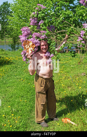 Carved handmade wood vase and spoon. Portrait of the woodcarver near lilac tree. Stock Photo