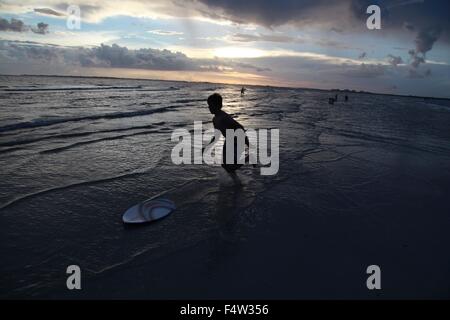 Fort Myers, Florida, USA. 9th Aug, 2013. A young boy skim boarding on the beach and ocean shore break waves at sunset. Located along the Gulf of Mexico, just a short drive from Fort Myers, Sanibel Island is justly famed for its sunsets, lighthouse and luxurious resorts. By far, the most popular activity here is shelling you barely can walk a step on the beach without indulging in the so-called ''Sanibel Stoop'' to search for shells. © Ruaridh Stewart/ZUMA Wire/Alamy Live News Stock Photo