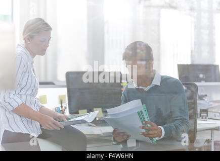 Business people reviewing paperwork at desk in office Stock Photo