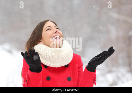Candid happy girl enjoying snow in winter wearing a red jacket Stock Photo