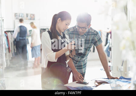 Photographer and fashion designer looking down at camera in sunny office Stock Photo
