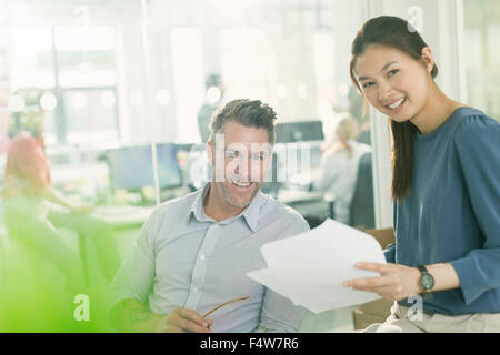 Portrait smiling business people reviewing paperwork in office Stock Photo