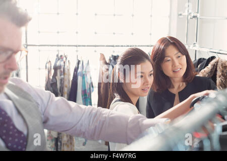 Fashion designers examining clothing on racks Stock Photo
