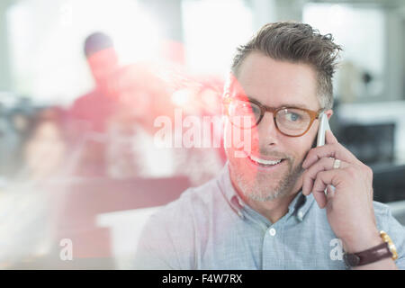 Smiling businessman talking on cell phone in office Stock Photo