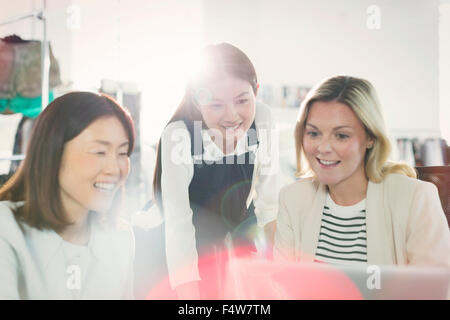 Smiling fashion designers working at laptop in office Stock Photo